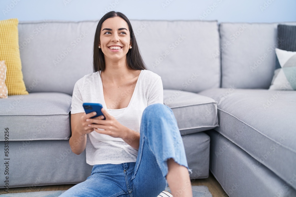 Young hispanic woman using smartphone sitting on floor at home Young hispanic woman using smartphone sitting on floor at home