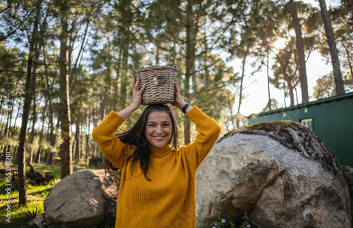 Smiling mature woman holding a wicker basket on top of her head photo