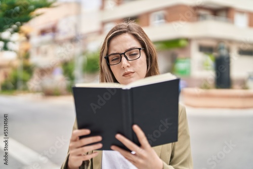 Young woman business worker reading book at street