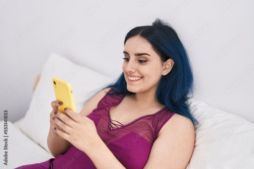 Young caucasian woman using smartphone sitting on bed at bedroom Young caucasian woman using smartphone sitting on bed at bedroom