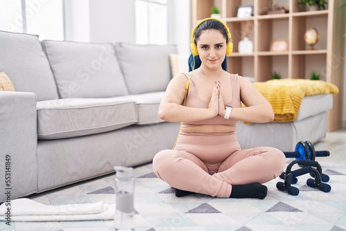 Young caucasian woman listening to music doing yoga exercise at home