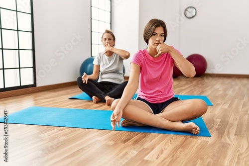Mother and daughter training yoga at sport center