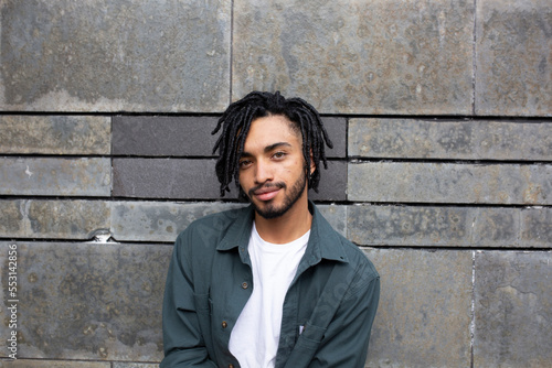Young man with dreads in front of wall