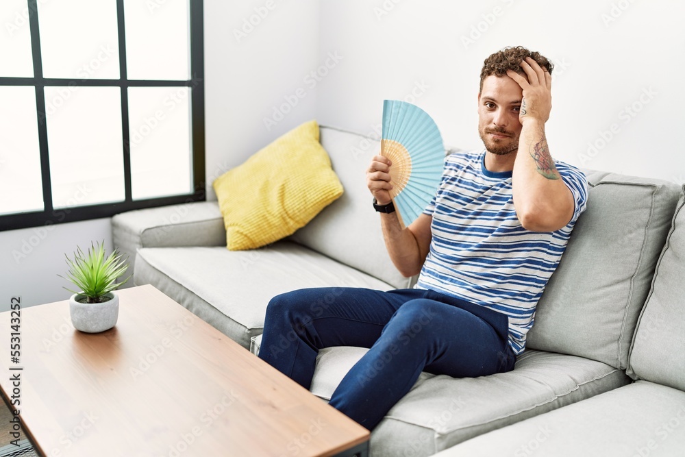Young hispanic man smiling confident using hand fan at home Young hispanic man smiling confident using hand fan at home