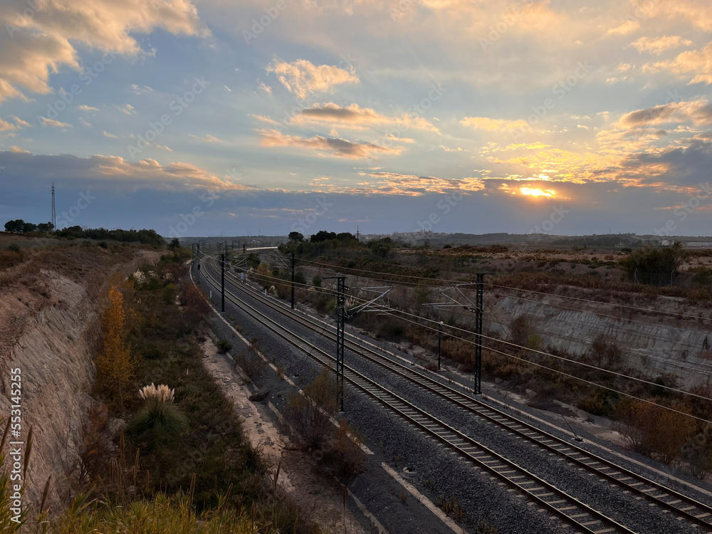 Railroad tracks in an industrial area at sunset