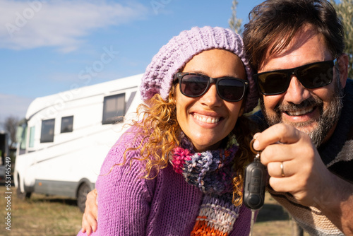 New camper van buyer people showing keys at the camera with happiness and big smile. Alternative home property buy and vacation with renting vehicle lifestyle. Mature an and woman smile together