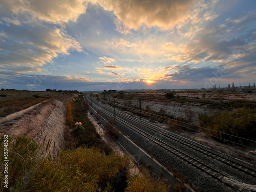 Railroad tracks in an industrial area at sunset