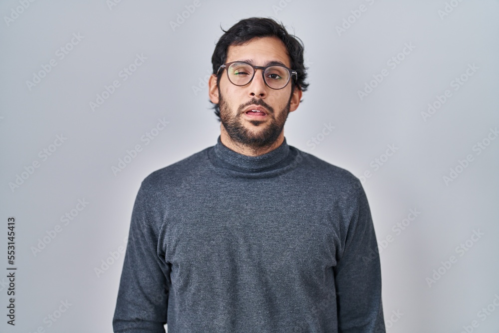 Handsome latin man standing over isolated background looking sleepy and tired, exhausted for fatigue and hangover, lazy eyes in the morning. Handsome latin man standing over isolated background looking sleepy and tired, exhausted for fatigue and hangover, lazy eyes in the morning.