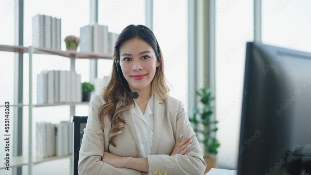 Smilling face of asian woman customer support agent or call center wearing headphone and works on desktop computer and crossed arms at office Smilling face of asian woman customer support agent or call center wearing headphone and works on desktop computer and crossed arms at office