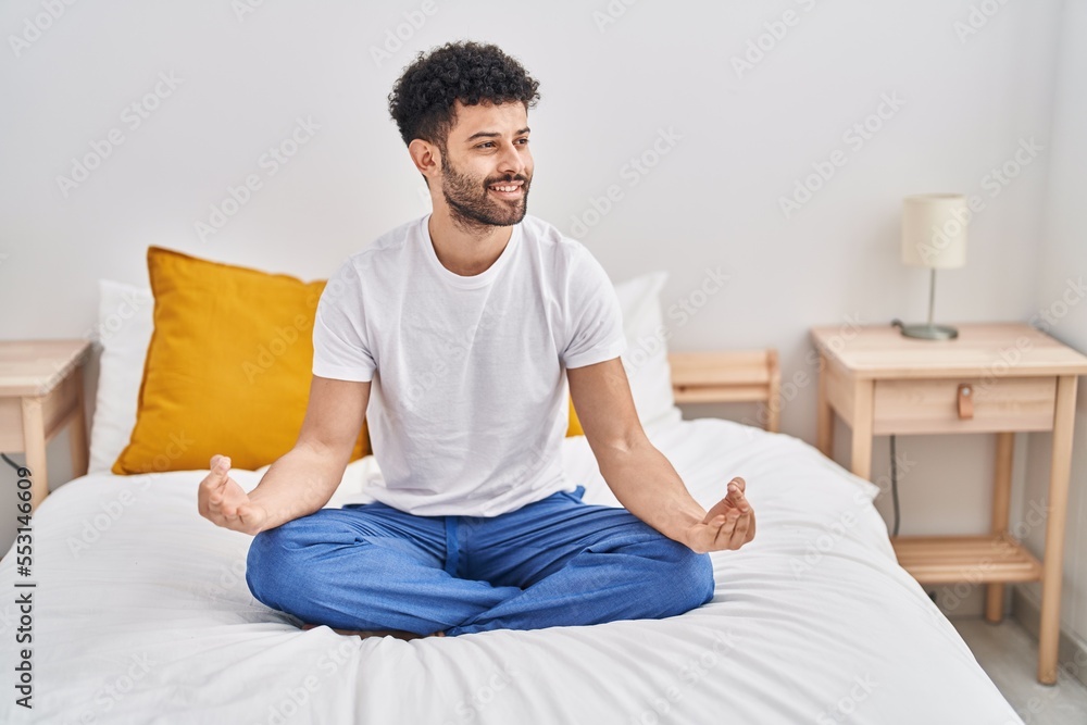 Young arab man doing yoga exercise sitting on bed at bedroom Young arab man doing yoga exercise sitting on bed at bedroom