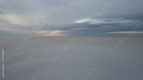 A heavenly ocean of clouds. Flying on a drone. The light yellow rays of the sun at sunset are reflected on the surface of the clouds. Double layer of clouds and heavy fog. Evening. Kazakhstan