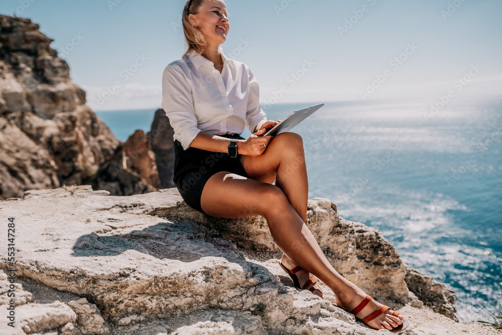 Digital nomad, Business woman working on tablet pc pad computer by the sea. Pretty lady with tablet pc on the sea, makes a business transaction online from distance. Freelance, remote work on vacation