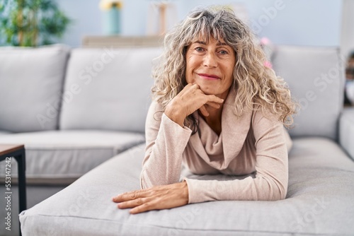 Middle age woman smiling confident lying on sofa at home