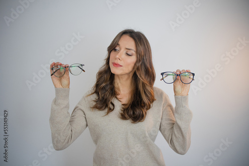 Fototapeta Person holding eyeglasses feeling undecided doubt choice