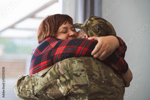 Fotografie Hispanic veteran soldier hugging his wife when returning from military service to home