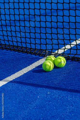 three balls close to the net of a blue paddle tennis court © Vic