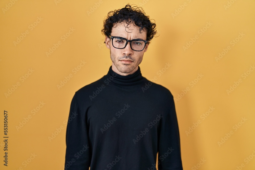 Fototapeta premium Hispanic man standing over yellow background skeptic and nervous, frowning upset because of problem. negative person.