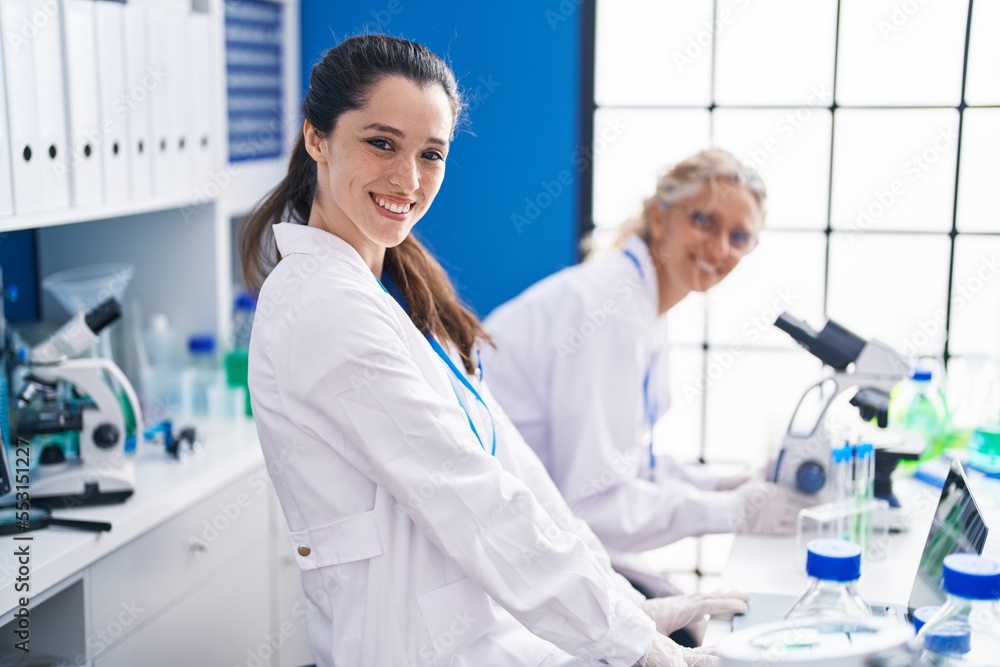 Two women scientists using microscope working at laboratory Two women scientists using microscope working at laboratory