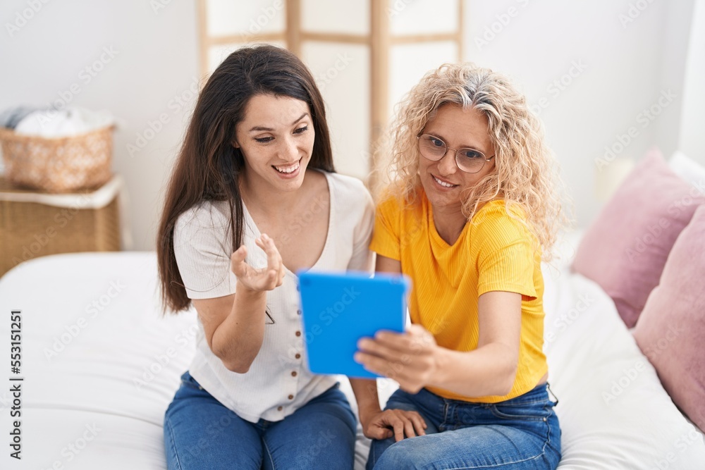 Two women mother and daughter having video call sitting on bed at bedroom Two women mother and daughter having video call sitting on bed at bedroom