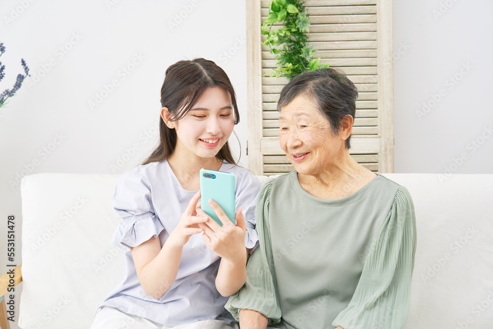 家でスマホを使う孫と祖母 家でスマホを使う孫と祖母
