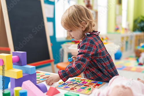 Adorable caucasian girl playing with maths game puzzle standing at kindergarten