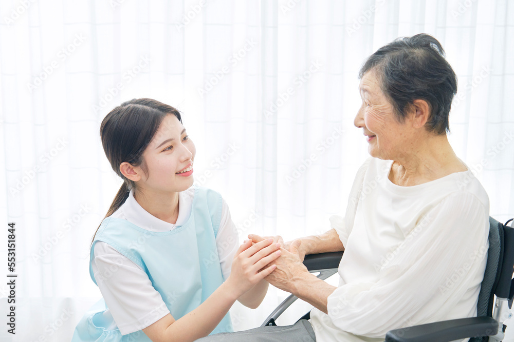 Fototapeta premium 車椅子に乗る高齢者女性と会話する介護士