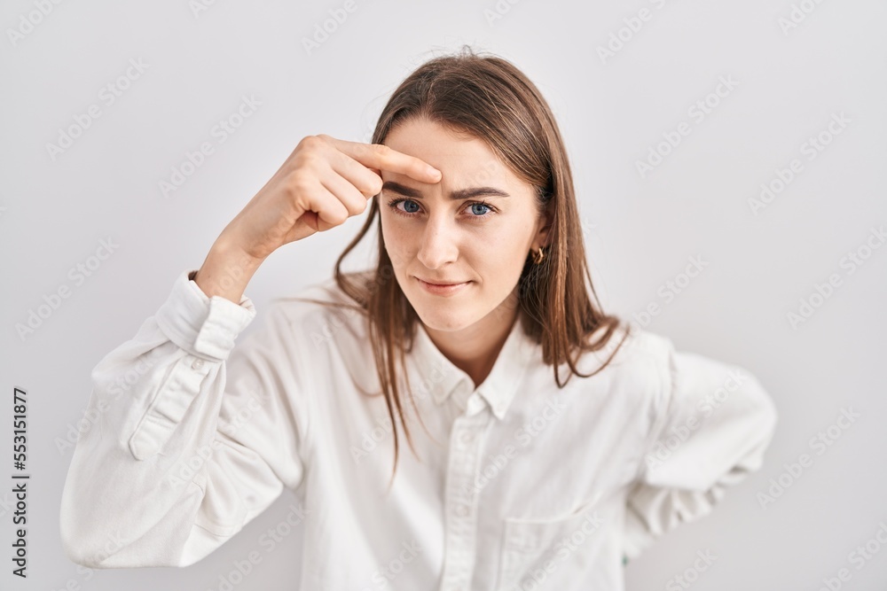 Young caucasian woman standing over isolated background pointing unhappy to pimple on forehead, ugly infection of blackhead. acne and skin problem Young caucasian woman standing over isolated background pointing unhappy to pimple on forehead, ugly infection of blackhead. acne and skin problem