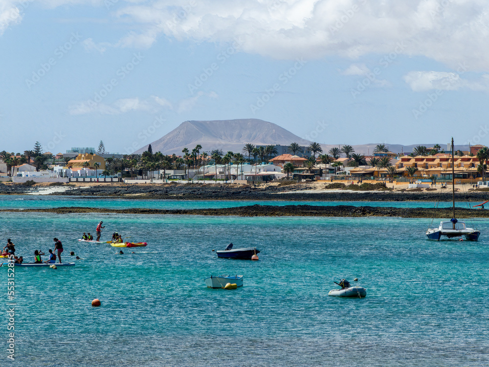Corralejo bay with boats, surf school and houses and mountains in the background, Spain