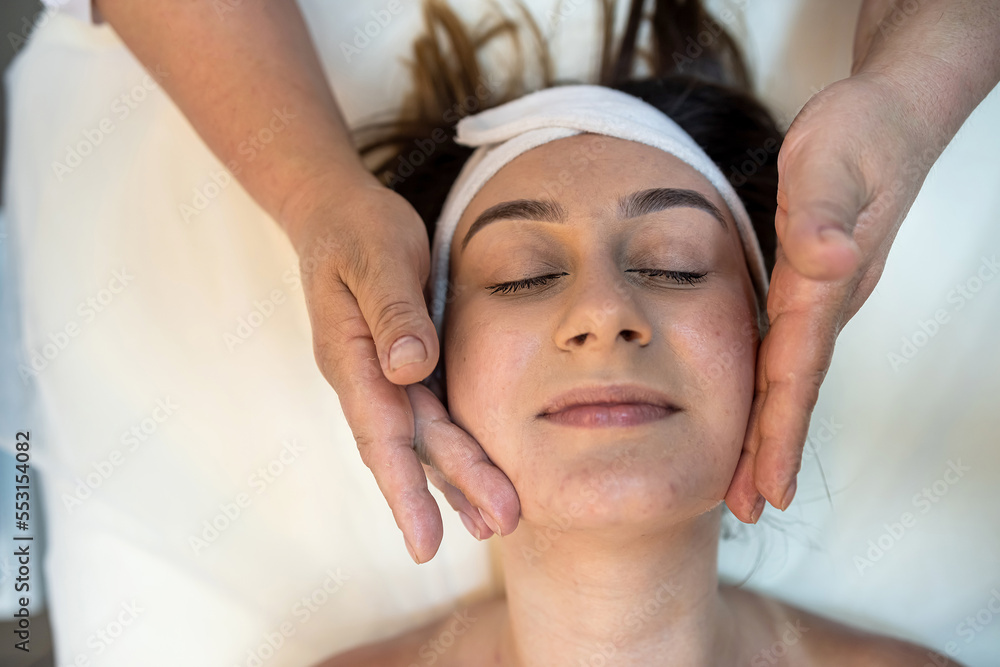 strong female masseur is doing a cosmetology facial massage to a client.