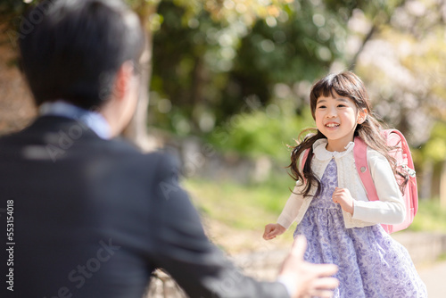 ランドセルを背負った女の子とスーツを着た父親