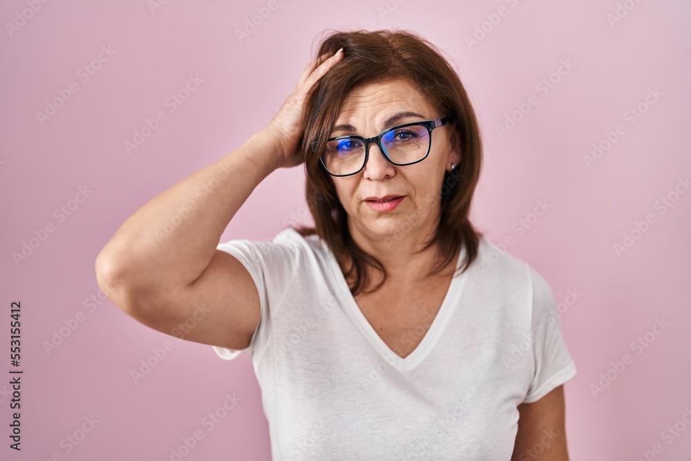 Middle age hispanic woman standing over pink background looking sleepy and tired, exhausted for fatigue and hangover, lazy eyes in the morning.