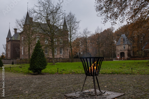 a fire burns on the grounds of the historic building Zuylen castle or slot Zuylen as it is called in Dutch on a cold winter day.  photo