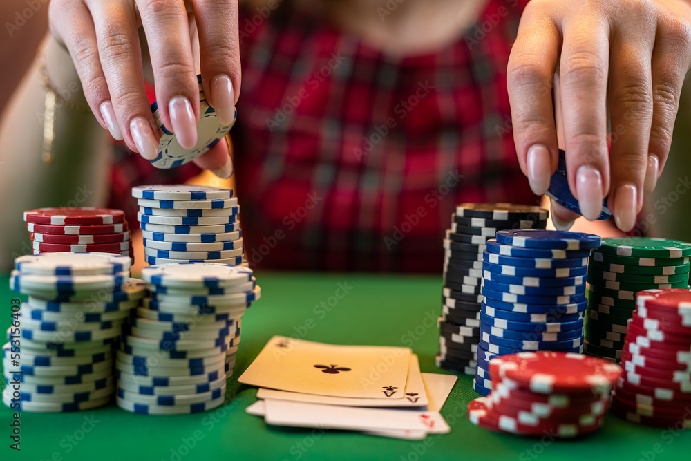 woman's hand with a manicure takes poker chips from a pile at a round poker table. woman's hand with a manicure takes poker chips from a pile at a round poker table.