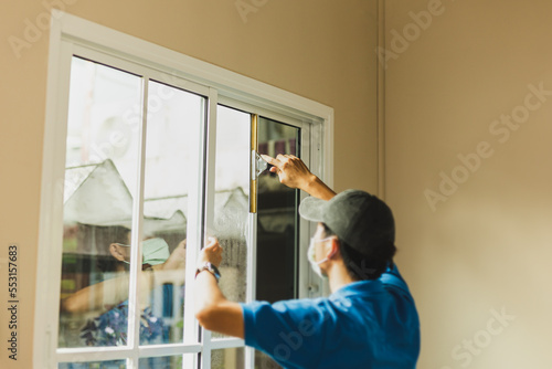 Obraz na plátně Worker use scraper cleaning window before installing tinting window film