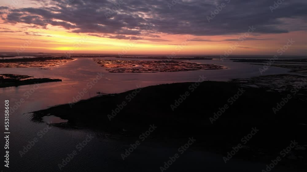 A high angle aerial view of a bay on Long Island, NY at sunrise. The camera pan left slowly, viewing the marsh and calm reflective waters in the distance. It is a peaceful and cloudy morning. A high angle aerial view of a bay on Long Island, NY at sunrise. The camera pan left slowly, viewing the marsh and calm reflective waters in the distance. It is a peaceful and cloudy morning.