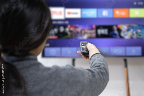 A woman experiences OTT service using a smart TV at home photo