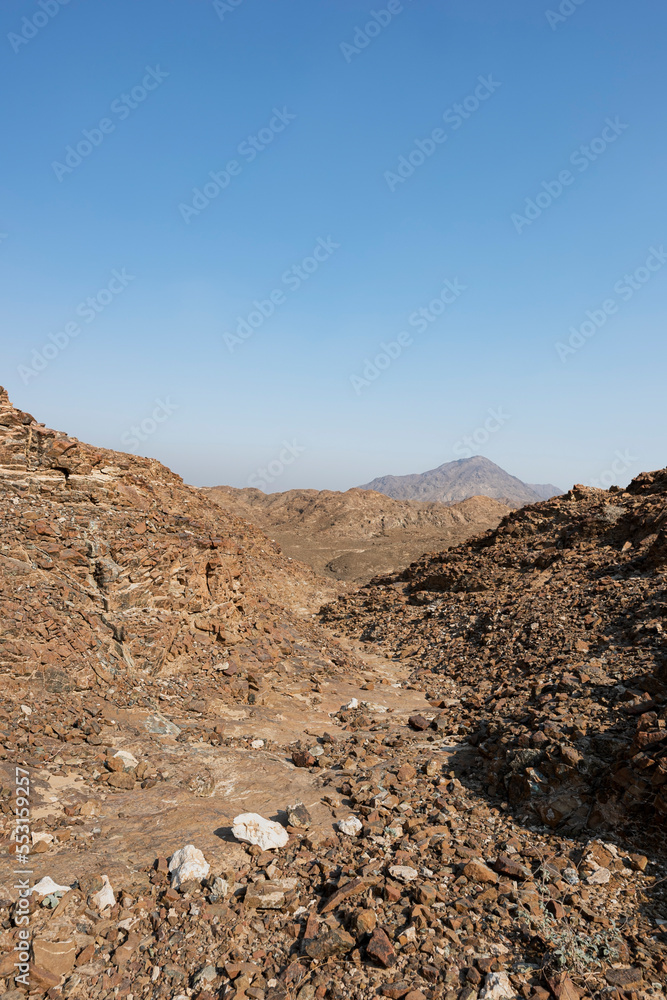 Dry riverbed in the Hajar Mountains of the United Arab Emirates with clear blue sky, UAE, rocky mountains with copy space