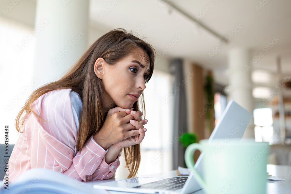 Beautiful smiling businesswoman reading something on a laptop while leaning on the table in the office Beautiful smiling businesswoman reading something on a laptop while leaning on the table in the office