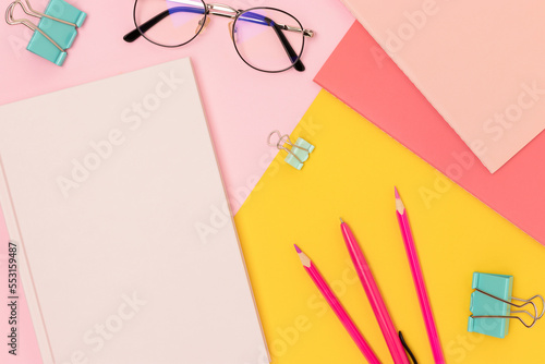 School supplies and eyeglasses on a pink and yellow background.