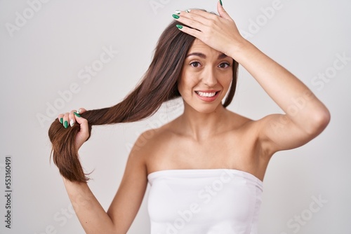 Young hispanic woman holding hair with hand stressed and frustrated with hand on head, surprised and angry face