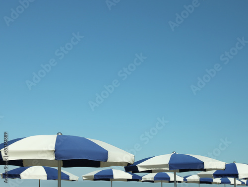 Fototapeta Naklejka Na Ścianę i Meble -  Many blue and white beach umbrellas near sea
