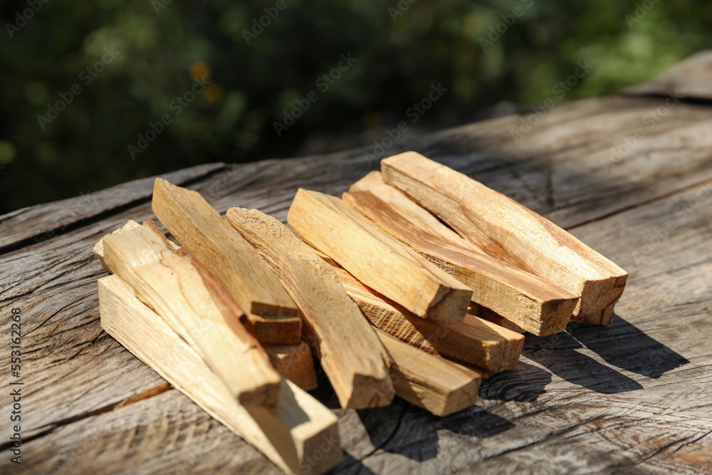 Palo santo sticks on wooden table outdoors, closeup