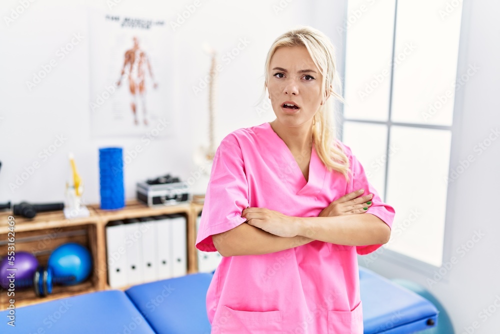 Young caucasian woman working at pain recovery clinic skeptic and nervous, disapproving expression on face with crossed arms. negative person. Young caucasian woman working at pain recovery clinic skeptic and nervous, disapproving expression on face with crossed arms. negative person.