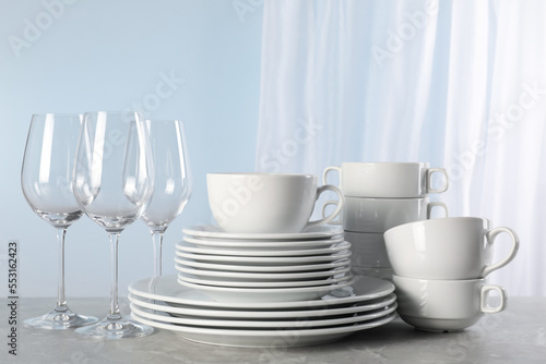 Set of clean dishware and glasses on grey marble table
