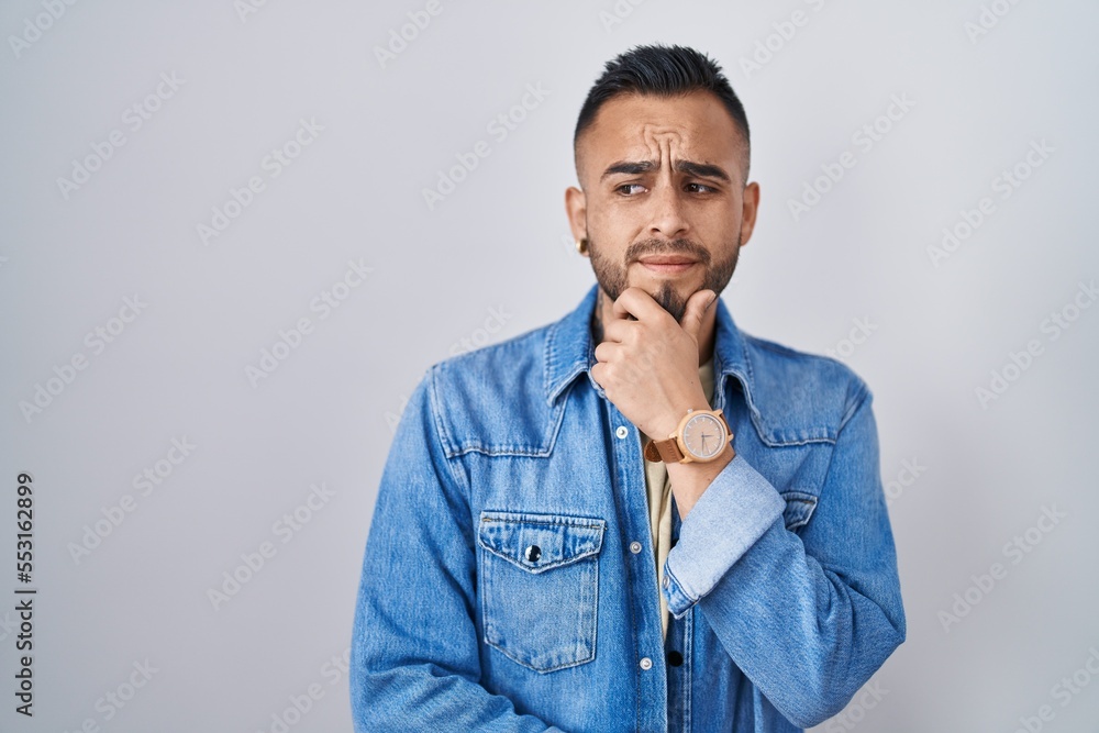 Young hispanic man standing over isolated background thinking worried about a question, concerned and nervous with hand on chin Young hispanic man standing over isolated background thinking worried about a question, concerned and nervous with hand on chin