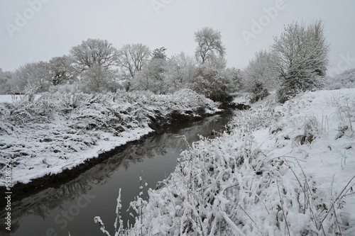 A cold, dull snow covered morning in Horley, Surrey by the River Mole on 12 Dec 2022.  photo