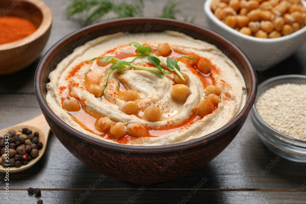 Delicious hummus with chickpeas and different ingredients on wooden table