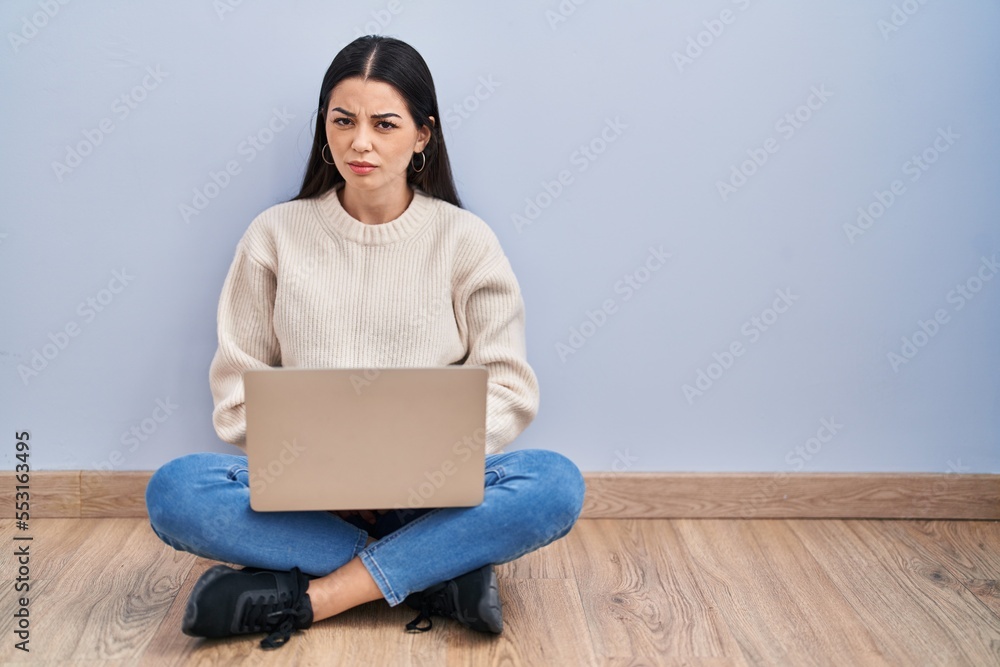 Young woman using laptop sitting on the floor at home skeptic and nervous, frowning upset because of problem. negative person. Young woman using laptop sitting on the floor at home skeptic and nervous, frowning upset because of problem. negative person.