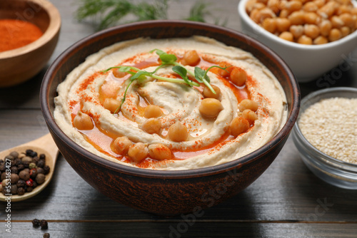 Delicious hummus with chickpeas and different ingredients on wooden table