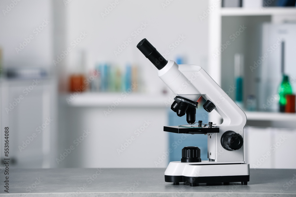 Modern medical microscope on grey table in laboratory, space for text Modern medical microscope on grey table in laboratory, space for text